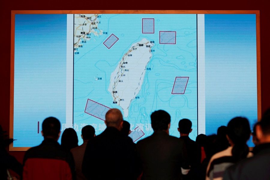 Visitors stand in front of a giant screen displaying a map of locations around Taiwan where mainland China's People's Liberation Army (PLA) conducted military exercises in August, at an exhibition titled "Forging Ahead in the New Era" during an organised media tour ahead of the 20th Party Congress of the Communist Party of China, in Beijing, China, 12 October 2022. (Florence Lo/Reuters)