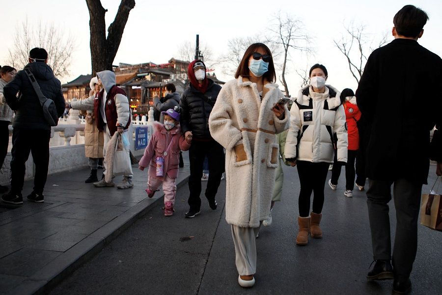 People walk by a lake amid the Covid-19 outbreak in Beijing, China, 31 December 2022. (Florence Lo/Reuters)