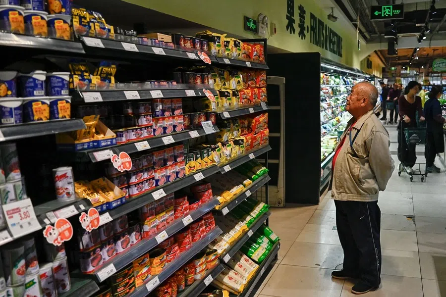 A man reads prices on products at a supermarket in Beijing on 15 April 2025.  (Pedro Pardo/AFP)