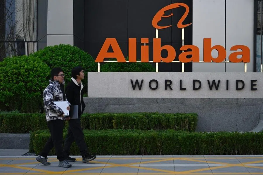 Employees walk past a company logo during a tour at the Alibaba office in Beijing on 1 April 2026. (Wang Zhao/AFP)