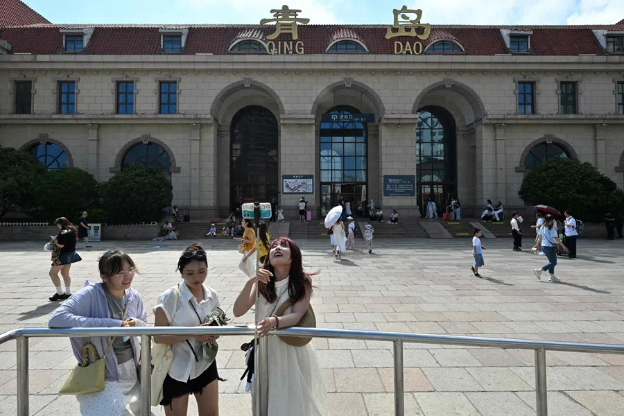 People take pictures outside a train station in Qingdao on 25 July 2025. (Adek Berry/AFP)
