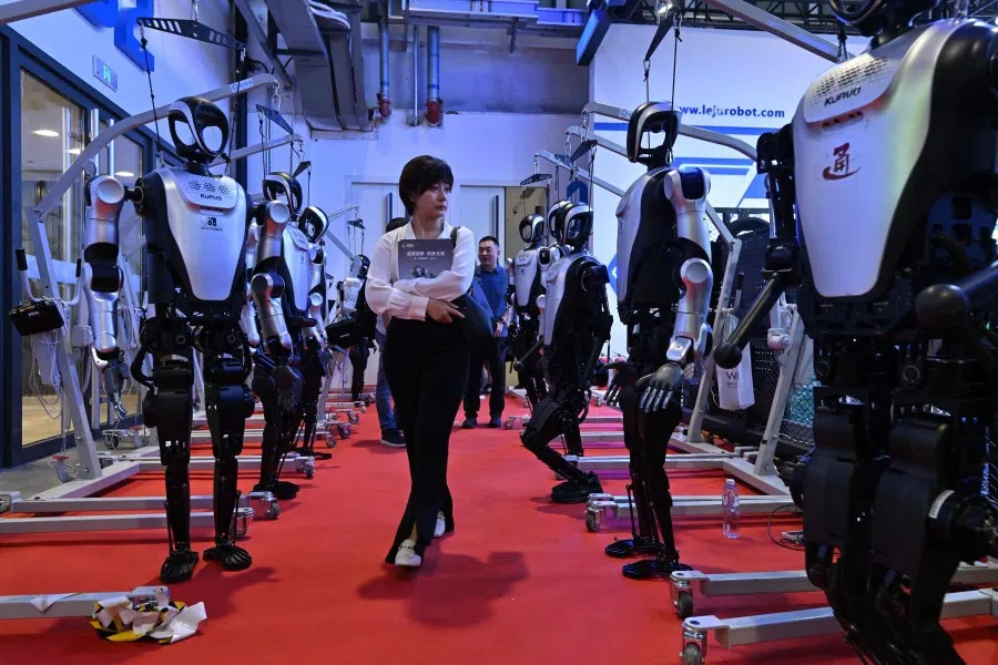 A woman walks robots during an exhibition as part of the 2025 World Robot conference in Beijing on 8 August 2025. (Adek Berry/AFP)