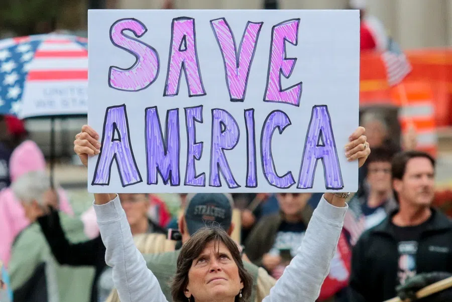 A supporter of former US President Donald Trump holds a sign as others gather outside the Michigan State Capitol to demand an audit of 2020 election votes, in Lansing, Michigan, US, 12 October 2021. (Rebecca Cook/Reuters)