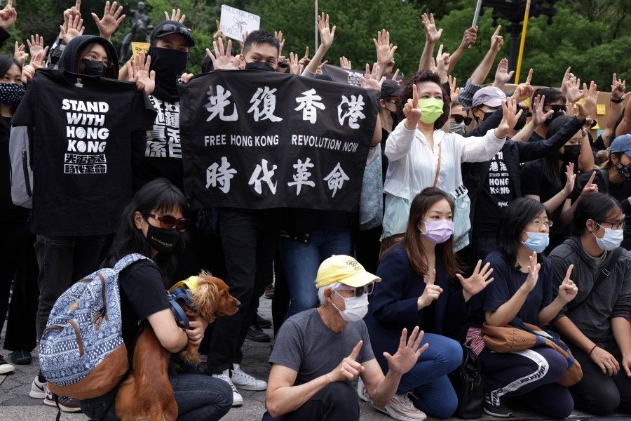 Hong Kongers gesture the "Five demands, not one less" protest motto as they gather during a rally at Union Square to support Hong Kong, 12 June 2021 in New York. (Alex Wong/AFP)