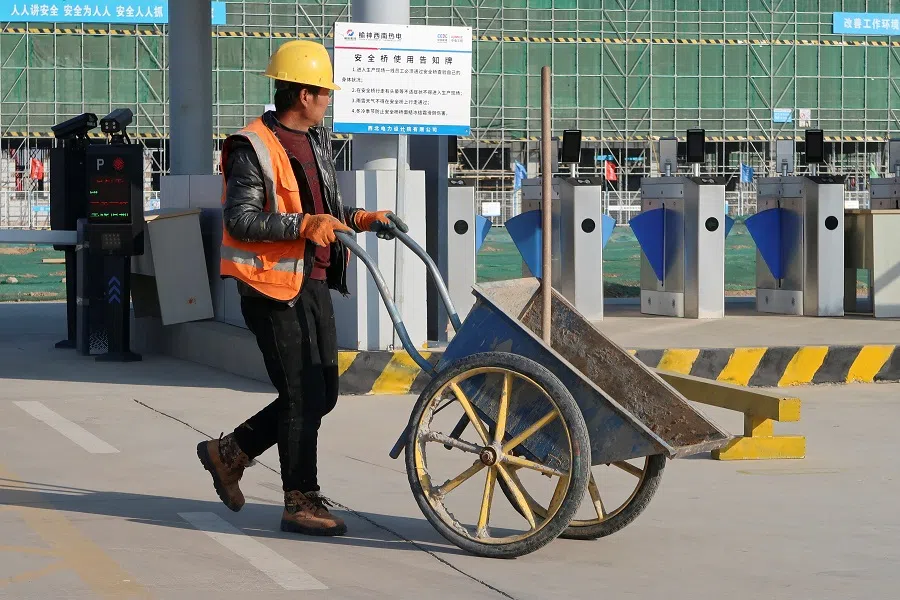 A construction worker pushes a wheelbarrow in front of the Yushen Yuheng power plant, a coal-fired power plant under construction, in Yulin, Shaanxi province, China, on 21 November 2023. (Colleen Howe/Reuters)