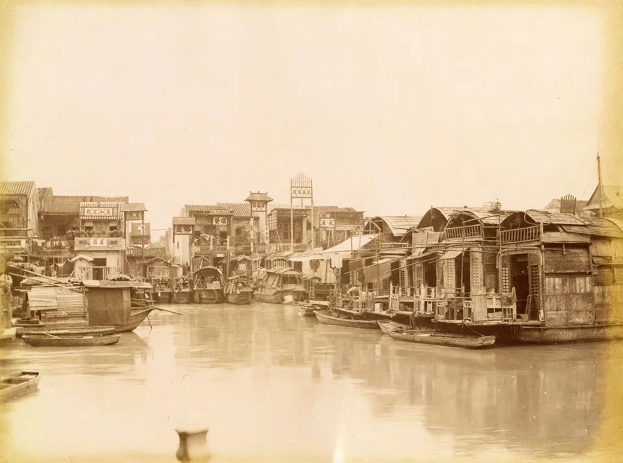 Buildings beside a tributary of the Pearl River in the 1880s. Houseboats and buildings on shore appear to merge together, providing temporary accommodation for merchants.