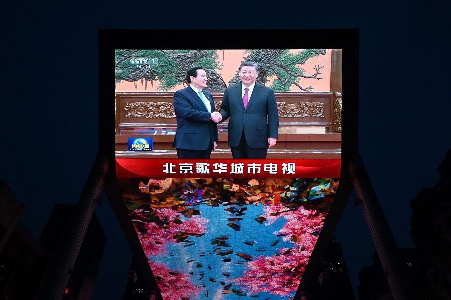 A large screen shows news coverage of Chinese President Xi Jinping (right) meeting former Taiwan President Ma Ying-jeou in Beijing on 10 April 2024. (Greg Baker/AFP)