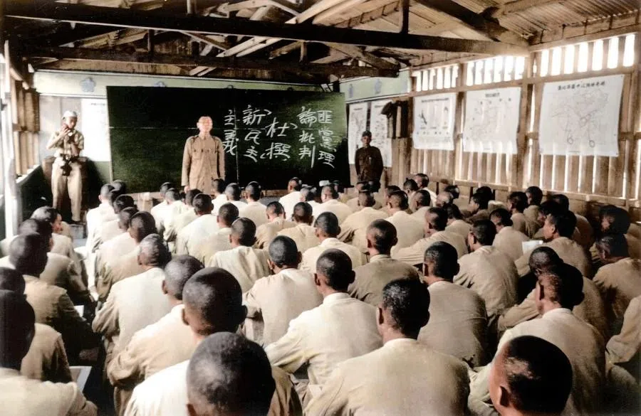 Political prisoners on Green Island attending a political study session, 1954. Written on the blackboard are: “Critique of Bandit-Gang Theory” and “Fabricating New Democracy”.