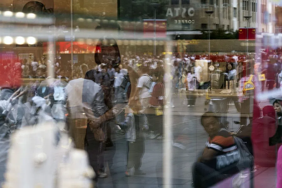 Shoppers reflected in a window on Nanjing East Road in Shanghai, China, 2 October 2024. (Qilai Shen/Bloomberg)