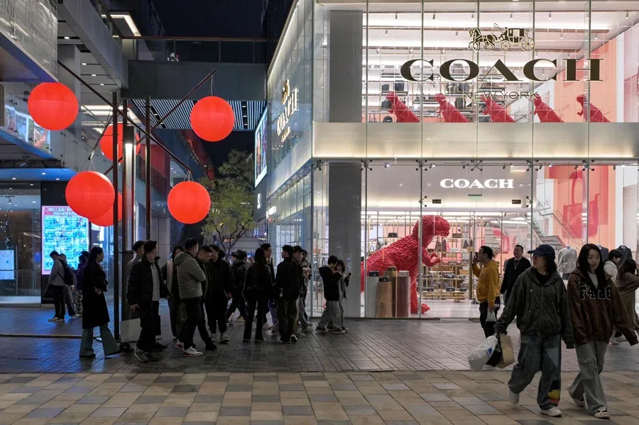 People walk past a store of the US luxury brand Coach, at the Sanlitun shopping area in Beijing, China, 30 October 2025. (Adek Berry/AFP)