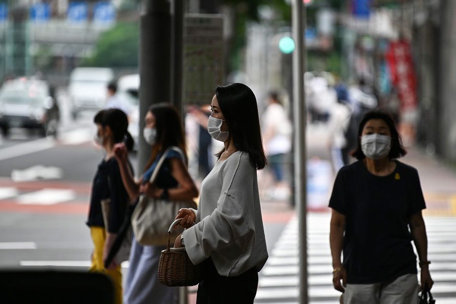 Face mask-clad pedestrians wait to cross a street in Tokyo on 24 July 2020. (Charly Triballeau/AFP)