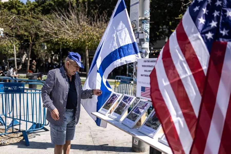 A man arranges an Israeli flag as he looks at the portraits of six US soldiers killed during the war with Iran, at a memorial on Dizengoff Square in Tel Aviv on 10 March 2026. The troops were killed on 1 March when a drone struck a key US command center in Kuwait, a day after the US and Israel launched a sweeping military campaign against Iran. (Olympia de Maismont/AFP)