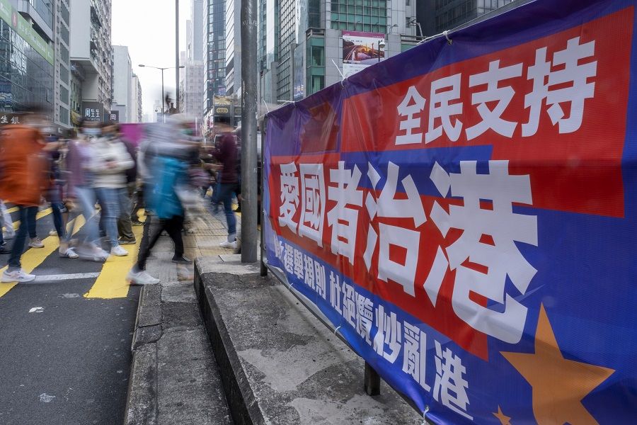 Pedestrians walk past a banner reading "The People Support Patriots Ruling Hong Kong" in the middle of a road in Hong Kong, China, on 6 March 2021. (Justin Chin/Bloomberg)