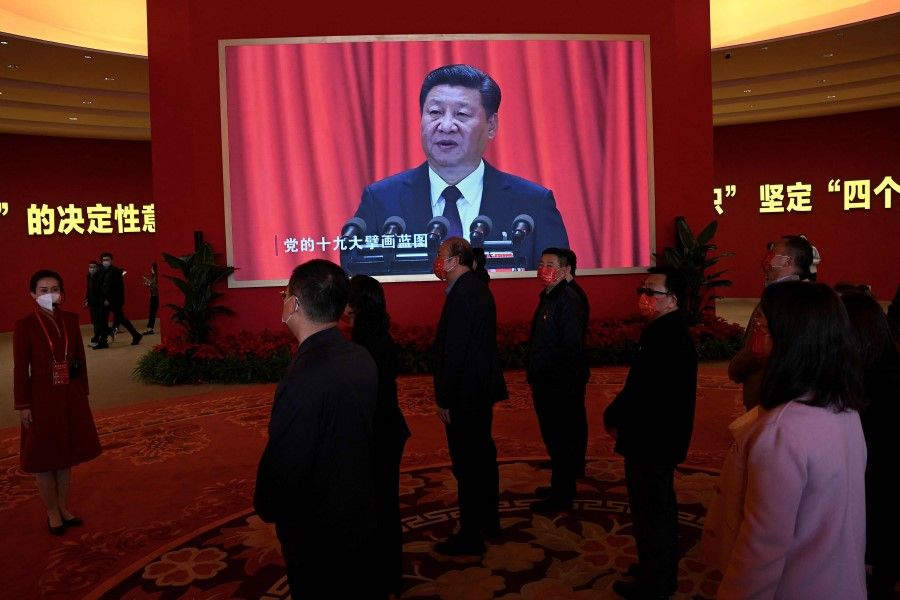 Visitors stand in front of a screen showing Chinese President Xi Jinping during the exhibition entitled "Forging Ahead in the New Era", showing the country's achievements during his past two terms, at the Beijing Exhibition Center in Beijing on 12 October 2022, ahead of the 20th Communist Party Congress meeting. (Noel Celis/AFP)