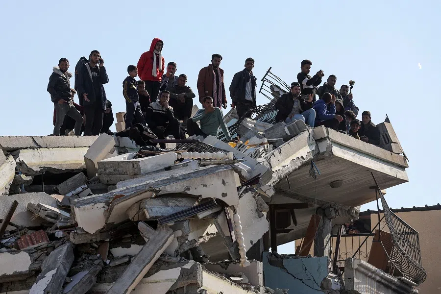 Palestinians gather on top of a damaged building in Khan Younis in the southern Gaza Strip, on 30 January 2025. (Ramadan Abed/Reuters)