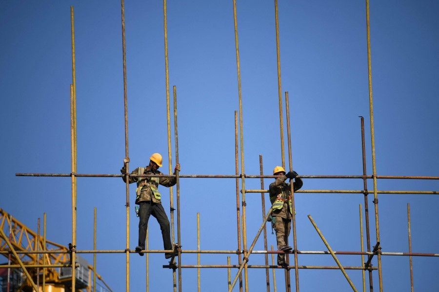 The Chinese government has made efforts to curb the number of white elephant projects in China. In this photo, workers balance on scaffolding at a construction site in Beijing on 14 April 2021. (Photo by Noel Celis / AFP)