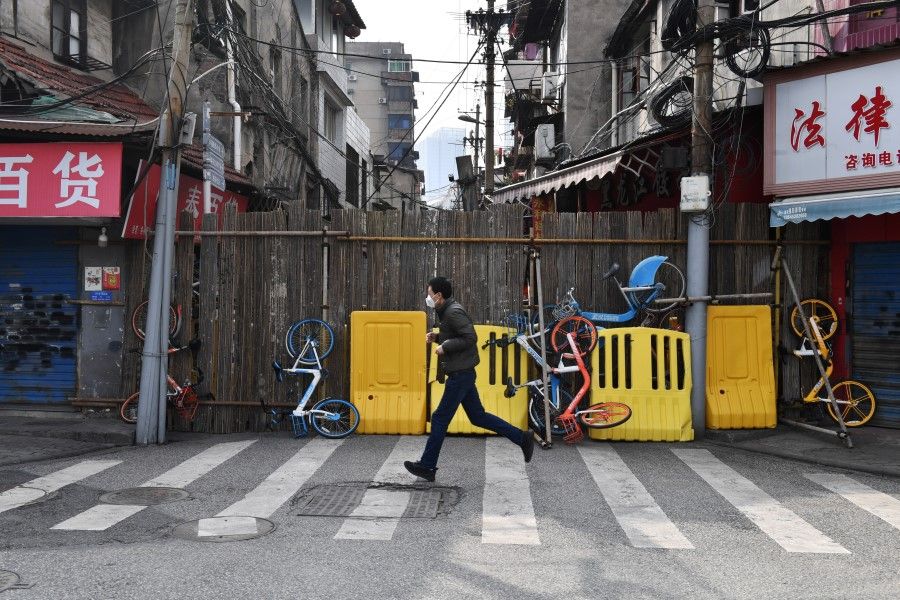 A man runs past a street blocked by barricades and shared bicycles in Wuhan. (Reuters)