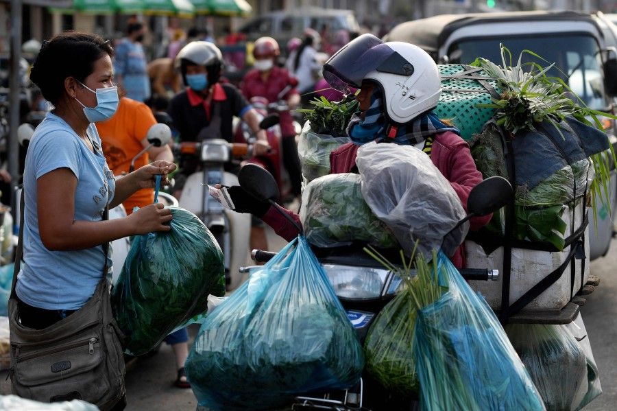 A woman buys vegetable along a street as markets remained closed amid lockdown restrictions introduced to try to halt a surge in cases of the Covid-19 coronavirus in Phnom Penh on 11 May 2021. (Tang Chhin Sothy/AFP)