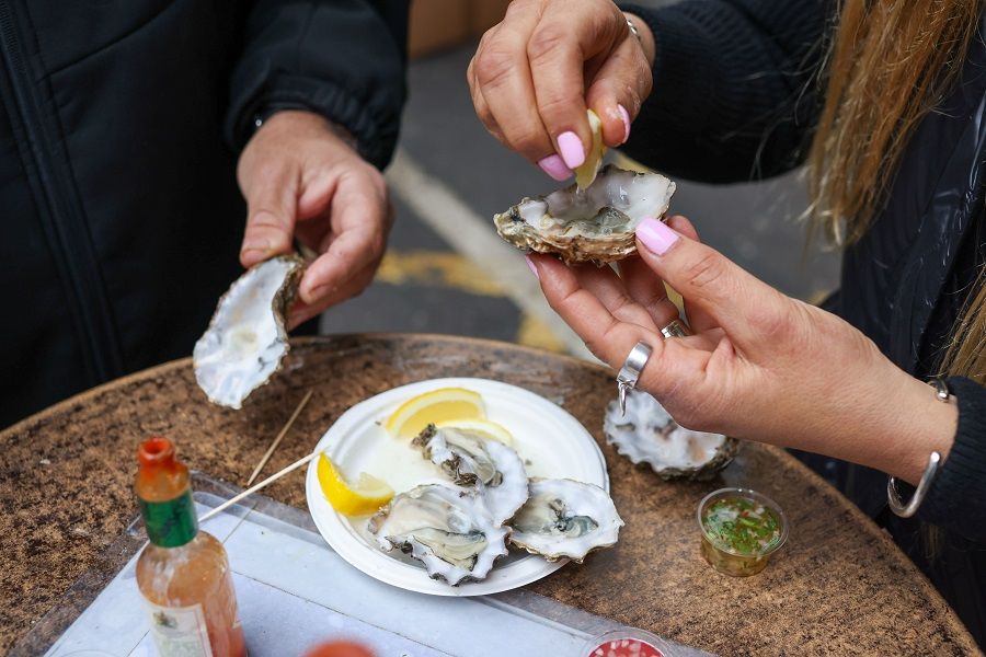Diners eat fresh oysters at Borough Market in London, UK, on 15 December 2021. (Hollie Adams/Bloomberg)