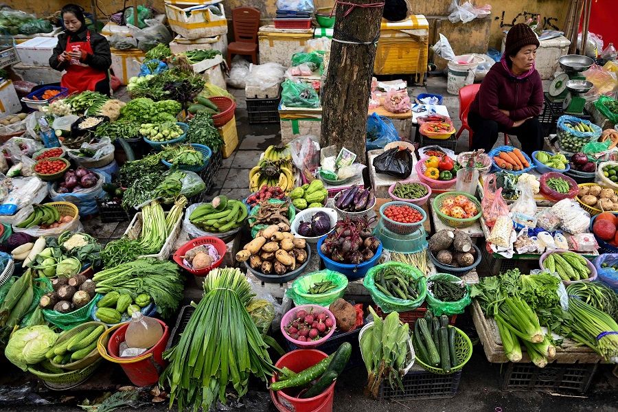Vegetable vendors wait for customers along a street in Hanoi on 12 January 2021. (Manan Vatsyayana/AFP)