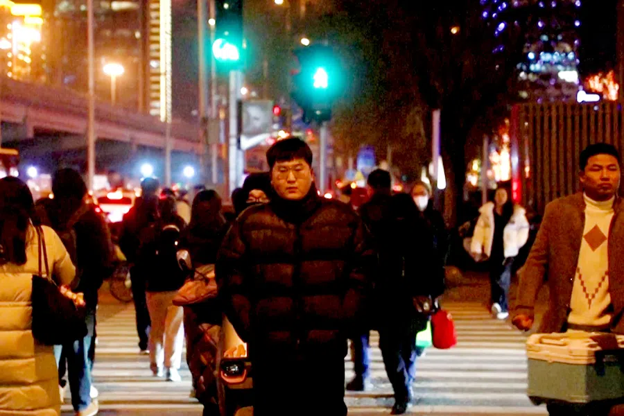 Youths walk on the street at night in Beijing, China, on 24 February 2024 (Screen grab from Reuters)