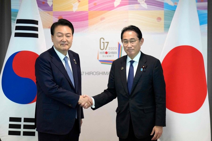 Japan's Prime Minister Fumio Kishida (right) and South Korean President Yoon Suk-yeol shake hands during their bilateral meeting as part of the G7 Leaders' Summit in Hiroshima on 21 May 2023. (Hiro Komae/AFP)