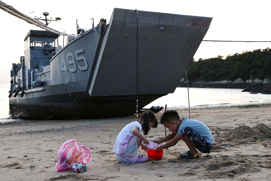 Children play with sand near a Taiwan Navy supply ship at a beach on Nangan island of the Matsu Islands in Taiwan, 16 August 2022. (Ann Wang/Reuters)
