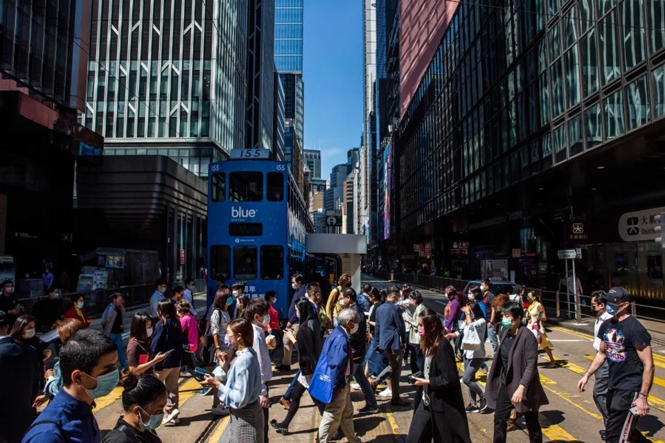 People cross a road in the Central district of Hong Kong on 25 October 2021. (Isaac Lawrence/AFP)