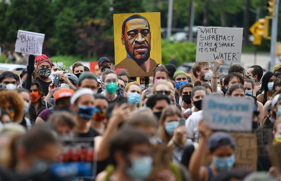 A protester holds up a portrait of George Floyd during a "Black Lives Matter" demonstration on 5 June 2020 in Brooklyn, New York. (Angela Weiss/AFP)