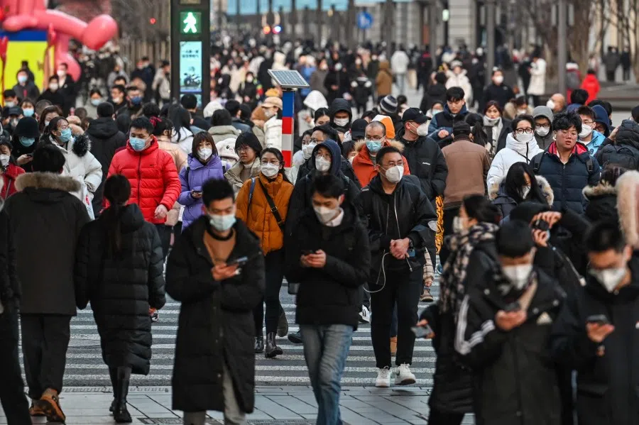 People walk on a pedestrian crossing on a street in the Huangpu district in Shanghai on 16 January 2023. (Hector Retamal/AFP)