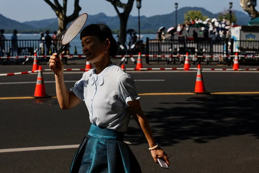 A person uses a hand fan to block the sunlight during an orange alert for high temperatures in Hangzhou, Zhejiang province, China, 31 July 2026.
