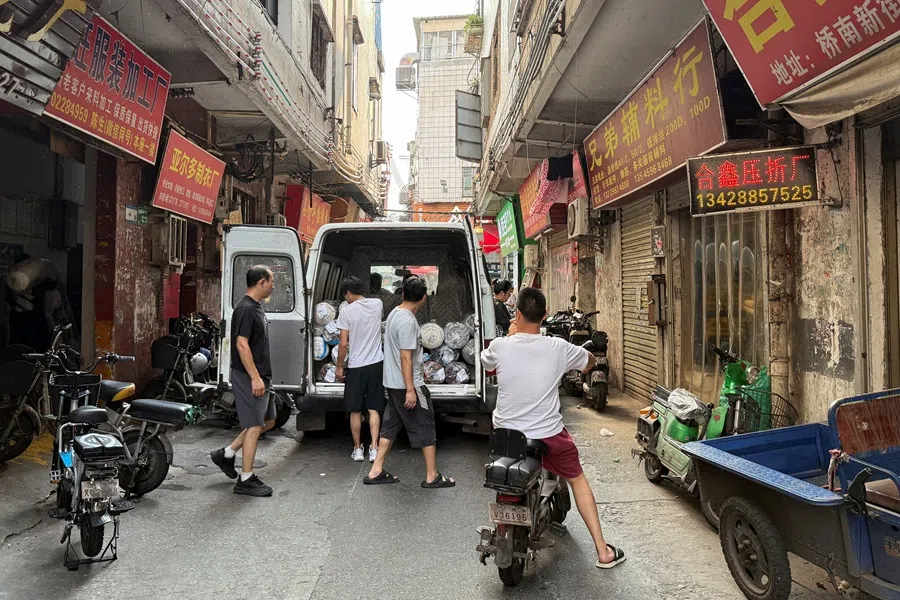 People unload material from a van outside a small-scale factory at Datang village in Guangzhou, Guangdong province, China, 27 July 2025. (David Kirton/Reuters)