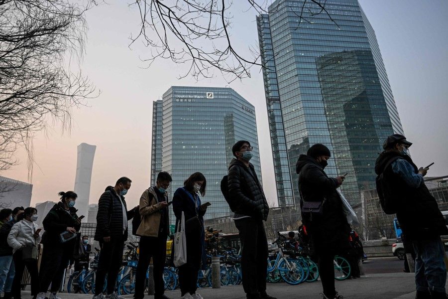 People wait for a bus in the central business district during rush hour in Beijing on 7 March 2023. (Jade Gao/AFP)