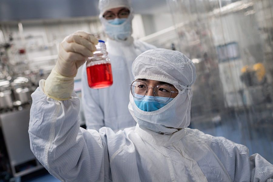 In this file picture taken on 29 April 2020, an engineer looks at monkey kidney cells as he makes a test on an experimental vaccine for the Covid-19 coronavirus inside the Cells Culture Room laboratory at the Sinovac Biotech facilities in Beijing. (Nicolas Asfouri/AFP)