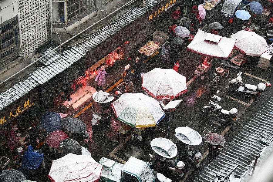 This photo taken on 15 January 2023 shows people holding umbrellas walking along a street during snowfall in Jiujiang, Jiangxi province, China. (AFP)