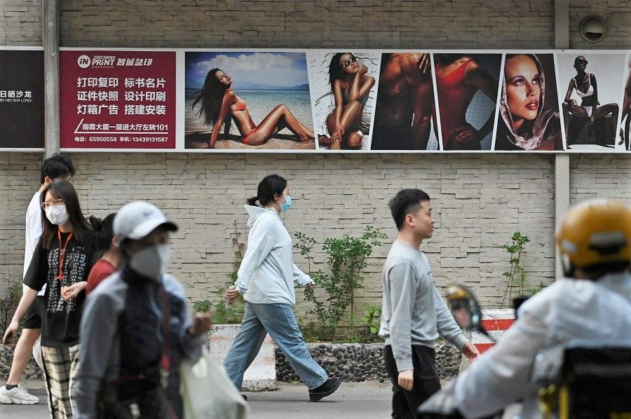 People walk past a tanning studio in Beijing, China, on 22 May 2023. (Greg Baker/AFP)