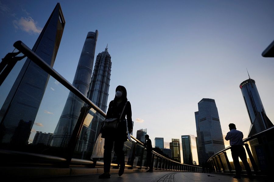People walk on an overpass past office towers in the Lujiazui financial district of Shanghai, China, 17 October 2022. (Aly Song/Reuters)