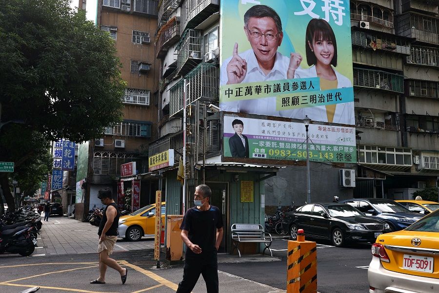 People walk by a building decorated with an election campaign poster showing Taiwan People's Party Ko Wen-je (left) and Wu Yi-hsuan in Taipei, Taiwan, 14 November 2022. (Ann Wang/Reuters)