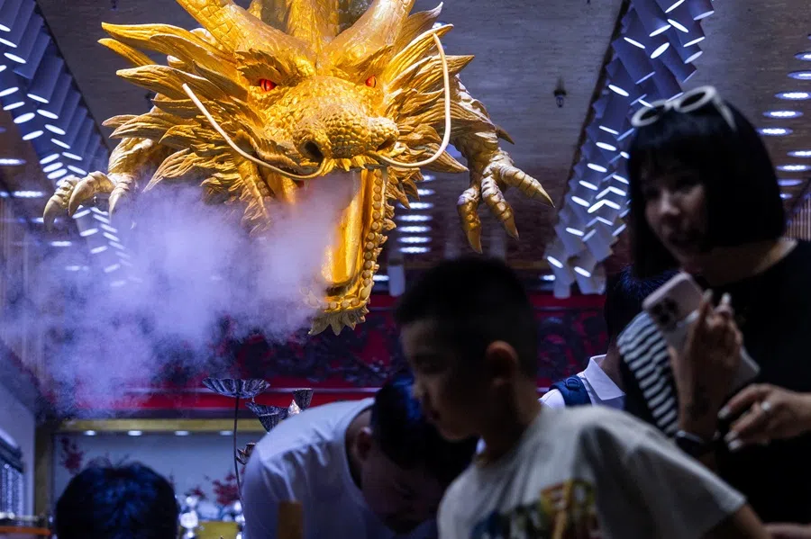 People walk next to a figure of a golden dragon in a store in Beijing, China, on 17 August 2025.