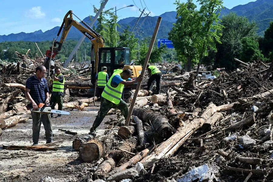 Workers clear debris following floods in Miyun district, northern Beijing, on 29 July 2025. (Adek Berry/AFP)