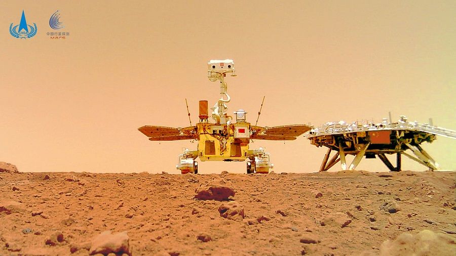 This undated handout photograph released on 11 June 2021 by the China National Space Administration (CNSA) shows an image taken by a camera released from China's Zhurong Mars rover showing the rover (left) and the landing platform on the surface of Mars. (Handout/China National Space Administration (CNSA)/AFP)