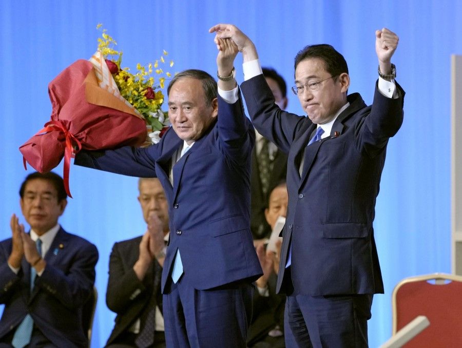 Japan's newly elected Liberal Democratic Party (LDP) leader Fumio Kishida and his predecessor Yoshihide Suga stand on stage following the LDP leadership vote in Tokyo, Japan, 29 September 2021. (Kyodo/via Reuters)
