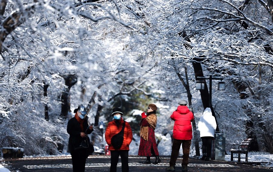 This photo taken on 13 November 2022 shows people visiting Beiling Park after snowfall in Shenyang, Liaoning province, China. (AFP)