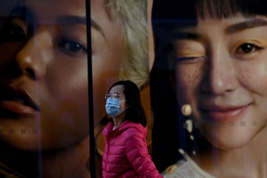 A woman walks past advertising at a shopping mall in Beijing, China, on 27 October 2021. (Noel Celis/AFP)