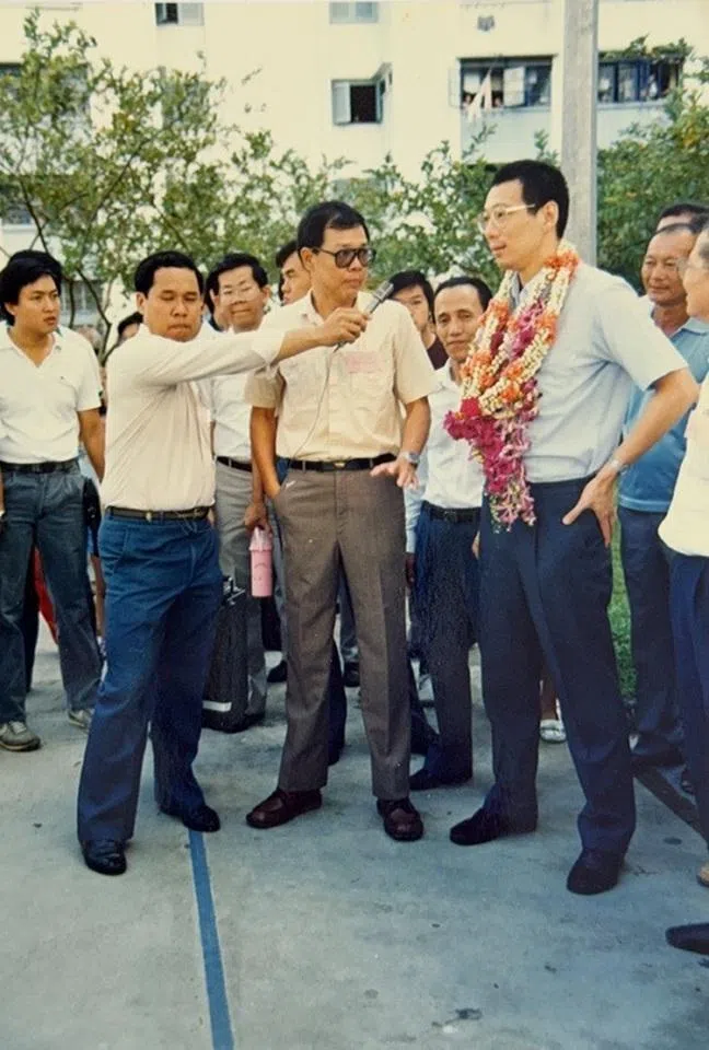 Minister for Trade and Industry Lee Hsien Loong visiting grassroots communities in 1987; at the time, the custom of presenting flower garlands as a welcome was still preserved locally.