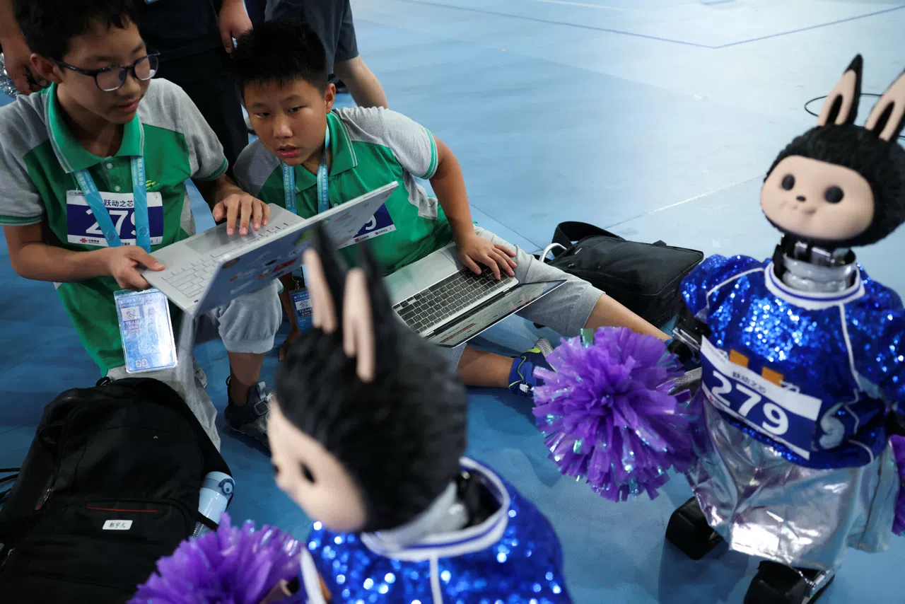 Students adjust humanoid robots before the cheerleading contest, during the 2026 World Humanoid Robot Games at the National Speed Skating Oval in Beijing, China, on 24 August 2026.
