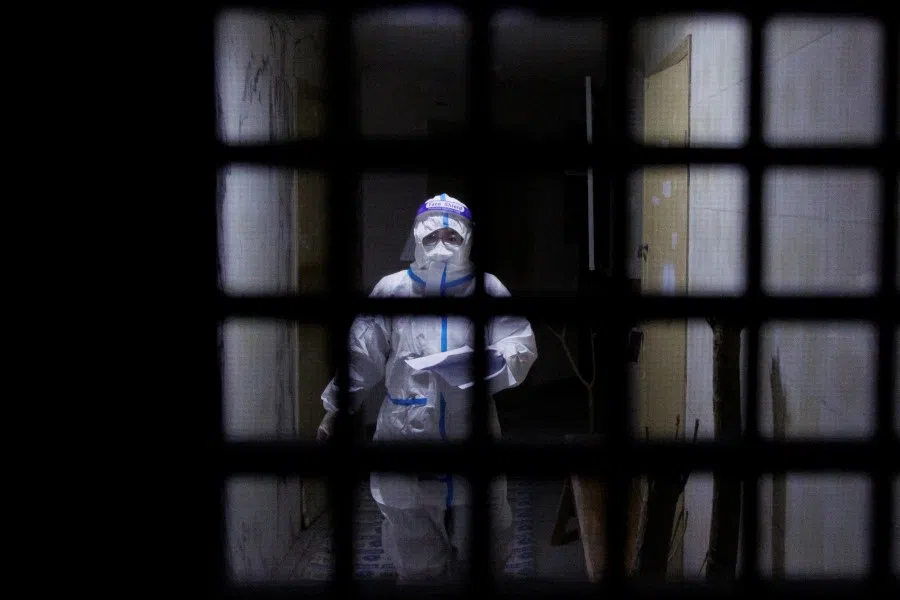 A pandemic prevention worker in a protective suit approaches an apartment in a building that went into lockdown as Covid-19 outbreaks continue in Beijing, 2 December 2022. (Thomas Peter/Reuters)