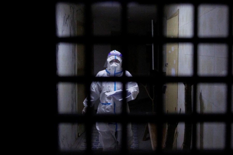 A pandemic prevention worker in a protective suit approaches an apartment in a building that went into lockdown as Covid-19 outbreaks continue in Beijing, 2 December 2022. (Thomas Peter/Reuters)