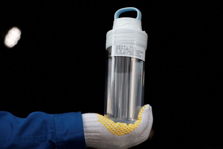 A Tokyo Electric Power Company (TEPCO) worker holds a sample of Advanced Liquid Processing System (ALPS) treated water in a bottle, at the disabled Fukushima Daiichi nuclear power plant in Okuma town, Fukushima prefecture, Japan, 8 March 2023.(Kim Kyung-Hoon/Reuters)