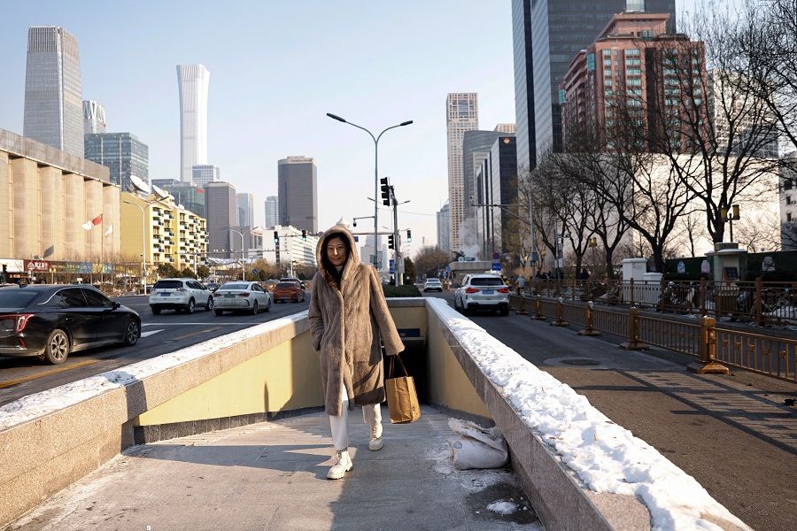 A woman walks on a street in Beijing's central business district in China, on 18 December 2023. (Tingshu Wang/Reuters)